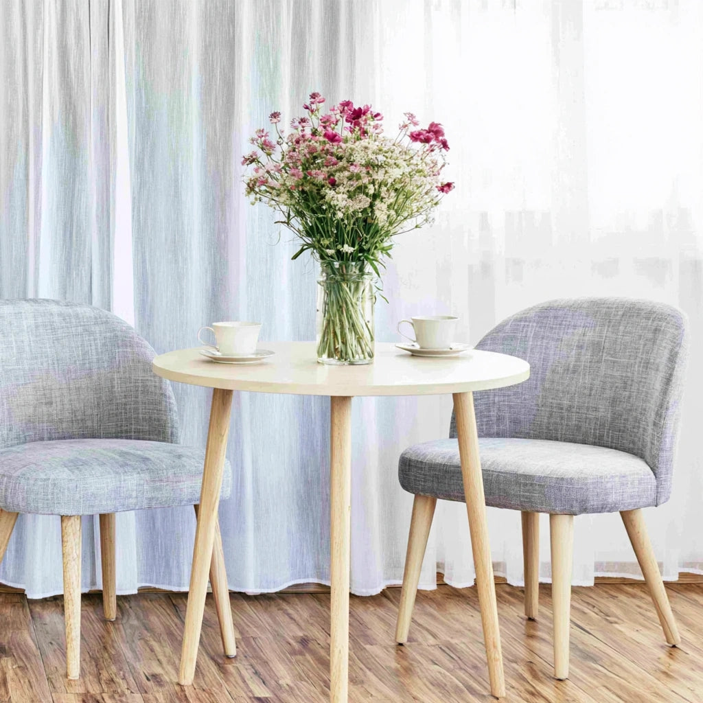 Light-colored round wooden side table from Zenoakstudio in a cozy living room seating area.