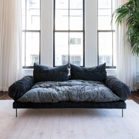 Dark gray velvet two-seater sofa with vertical ribbing, designed for living room comfort by Zenoakstudio.